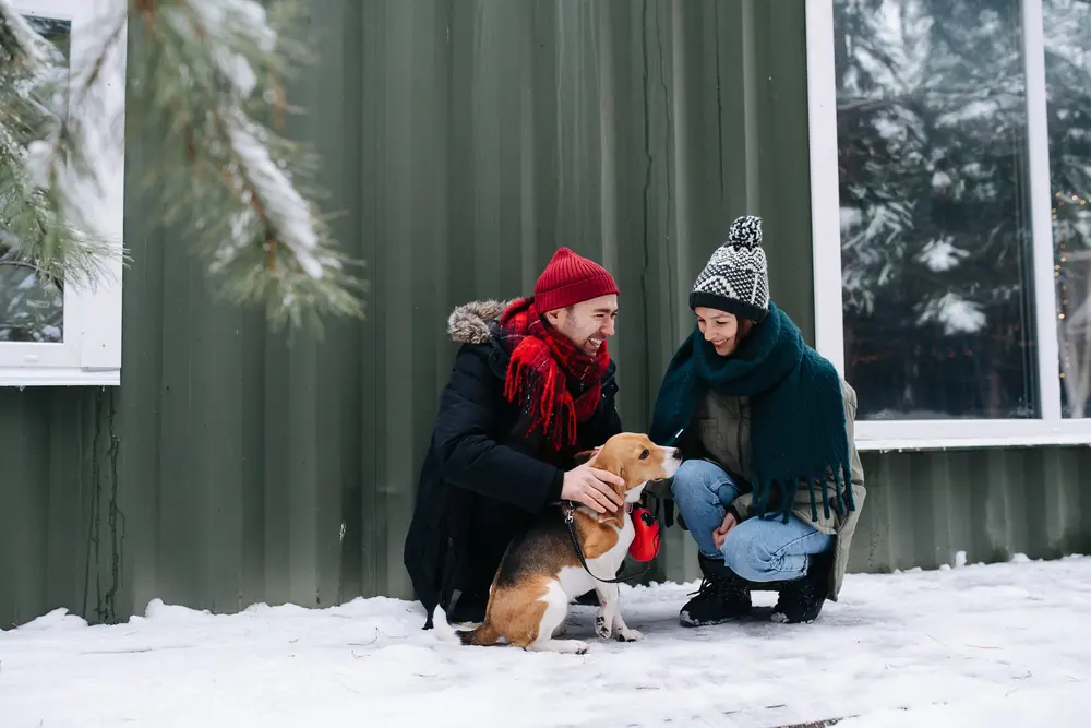 A family plays with their dog outside their home in the winter.